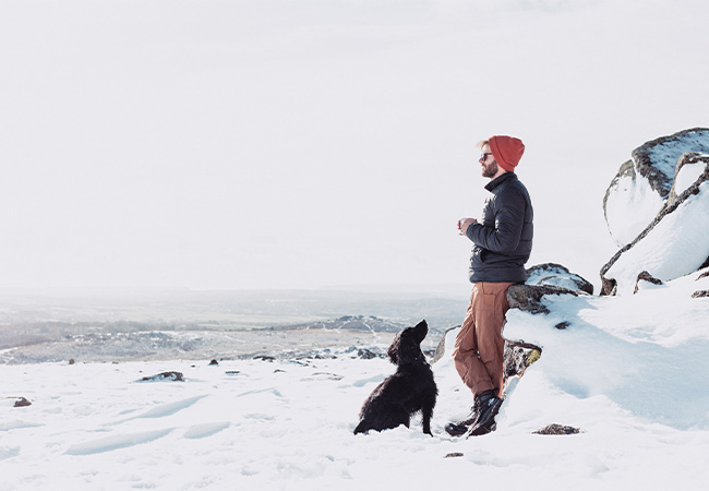 A person with their dog on Dartmoor in the snow